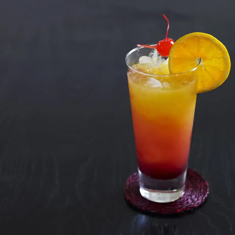 Tequila sunrise cocktail con fetta d'arancia e ciliegia