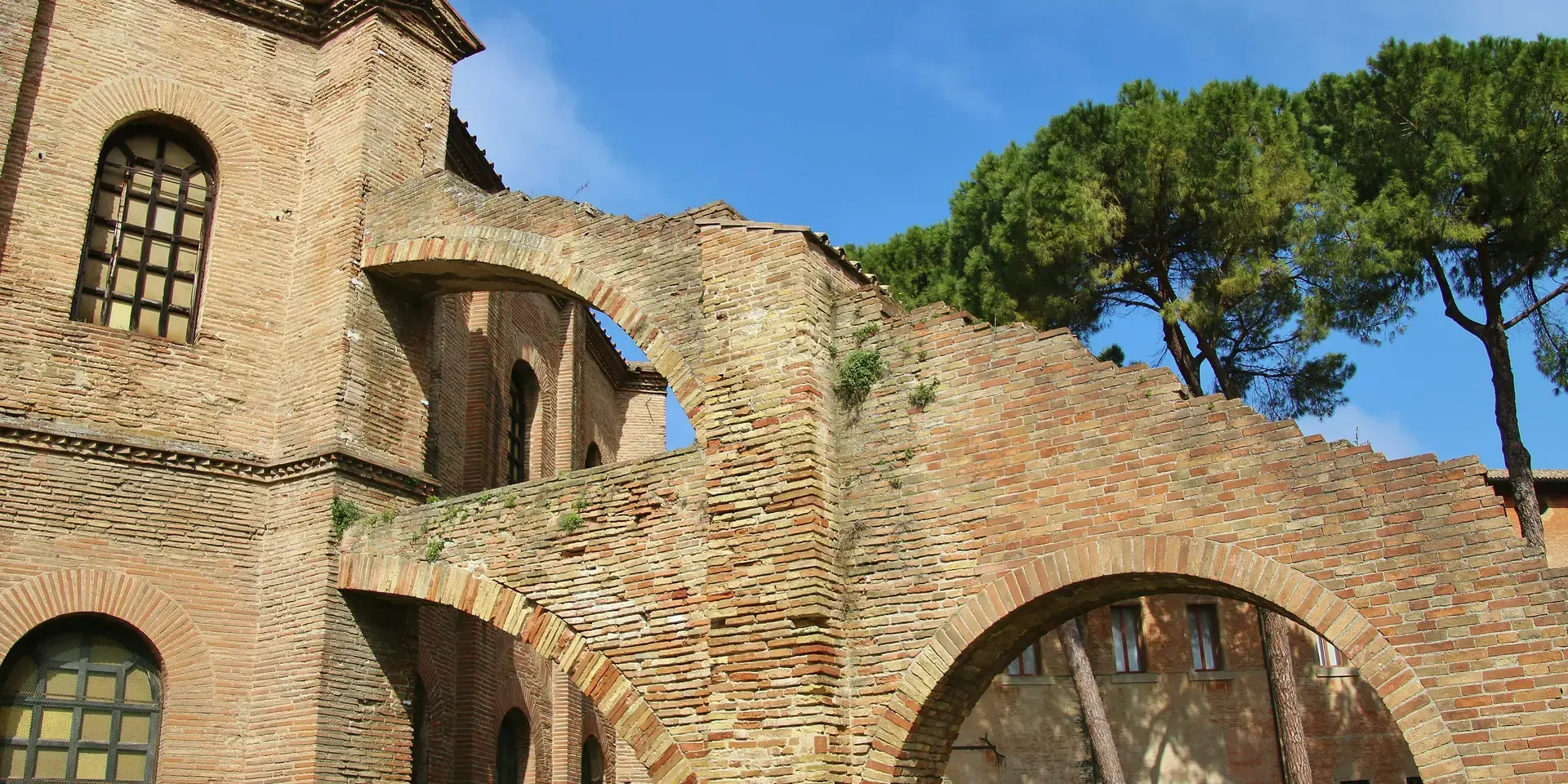 edificio in mattoni marroni vicino agli alberi verdi sotto il cielo blu durante il giorno