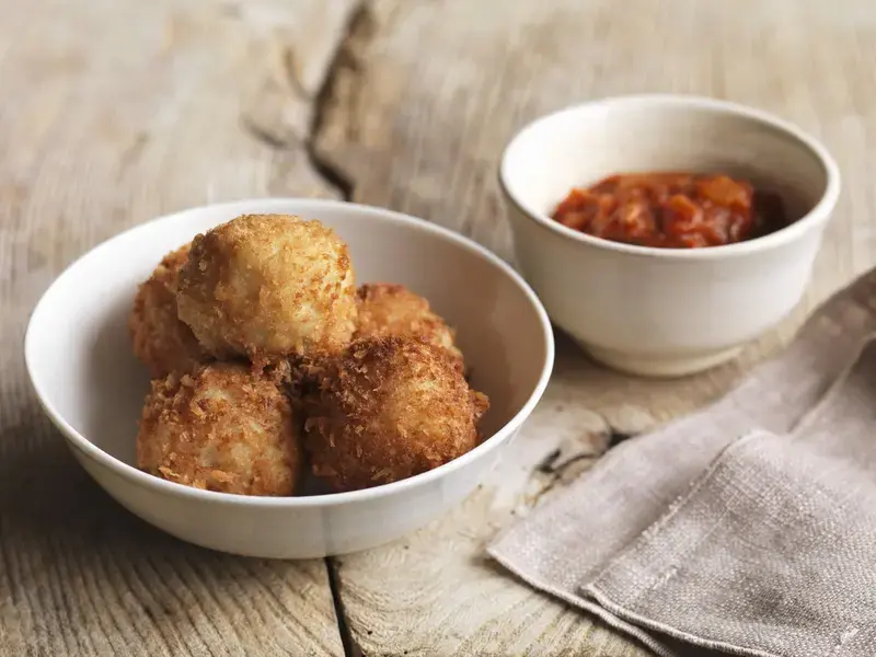 Polpette di riso fritte in ciotola bianca con salsa piccante