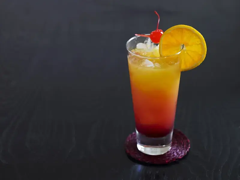 Tequila sunrise cocktail con fetta d'arancia e ciliegia